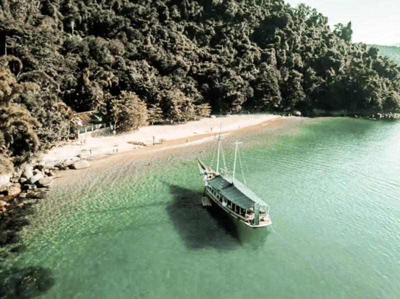 A wooden boat anchored off an empty beach