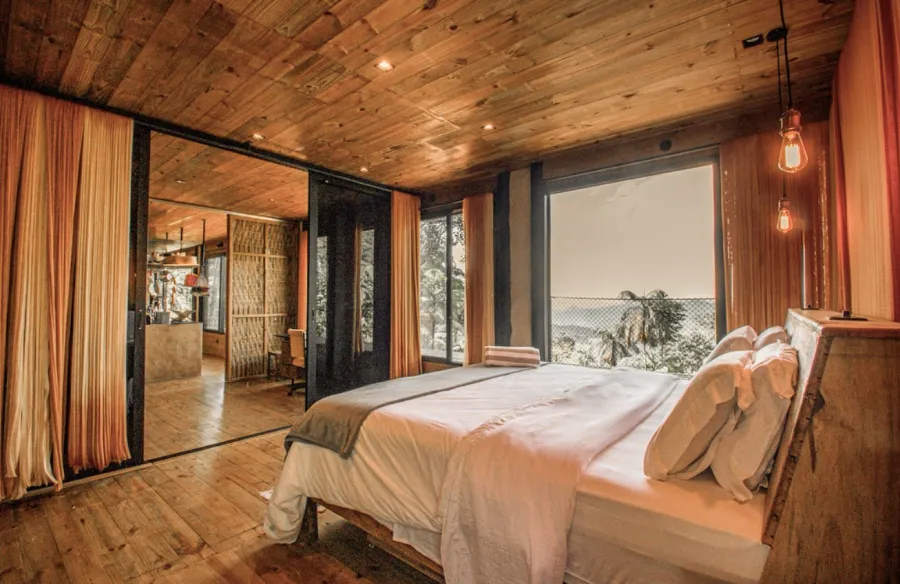 A bedroom in wood and glass looking into the forest