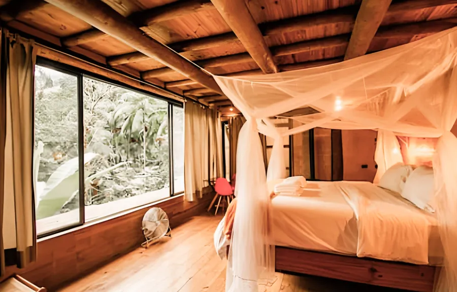 A private room with a canopy bed and forest windows at Aldeia Rizoma
