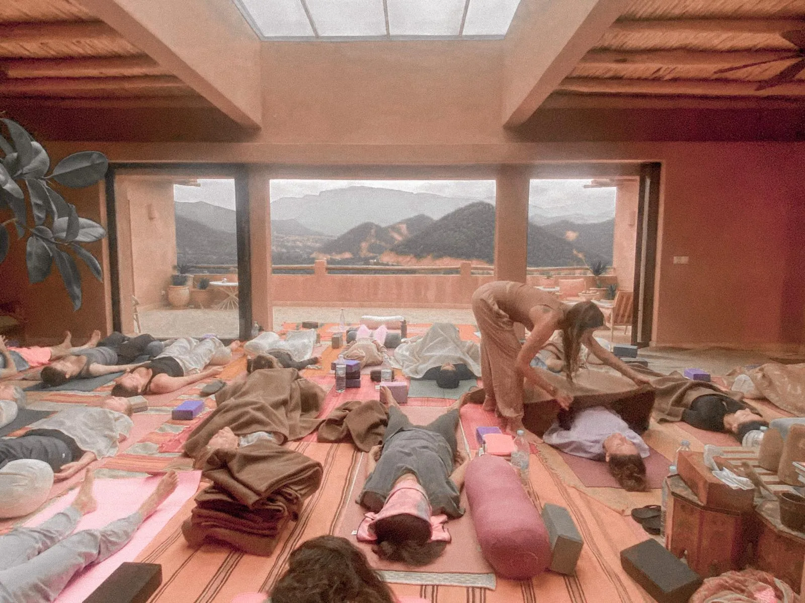 Brisa covering a student with a blanket during savasana